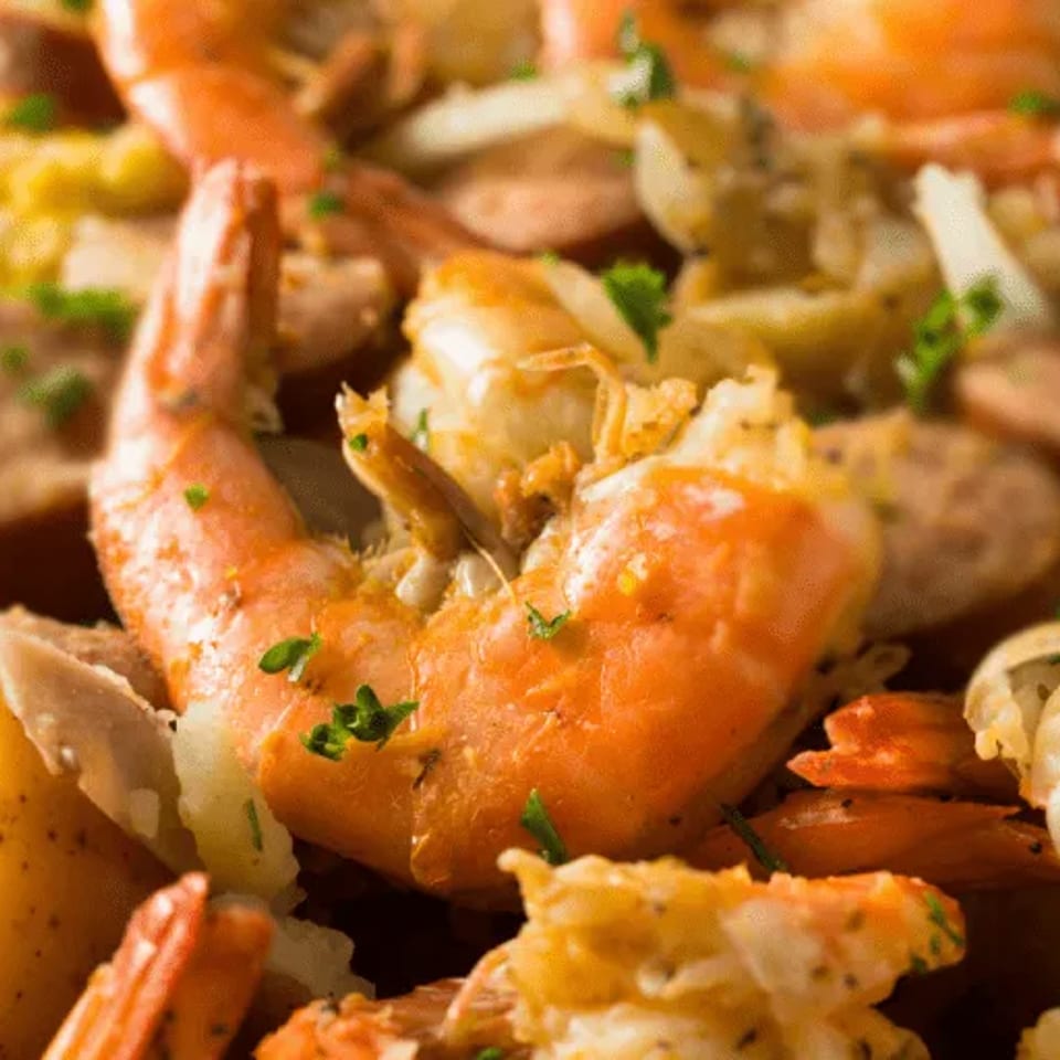 Close-up of a seafood boil with shrimp, sausage, corn on the cob, and potatoes.