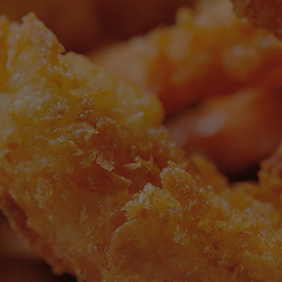 Close-up of golden-brown fried shrimp in a basket with white paper lining.
